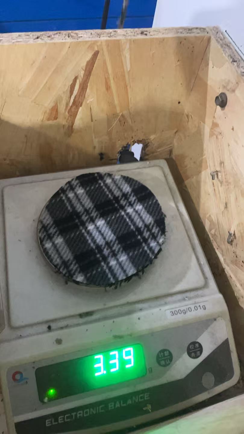 Weight test photo — black plaid sample; visible scale reading 3.39 g. Cut area and GSM calculation not shown.